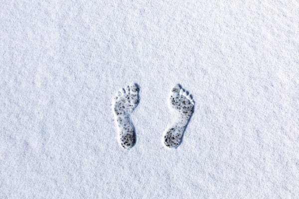 Overhead view of bare footprints in fresh snow