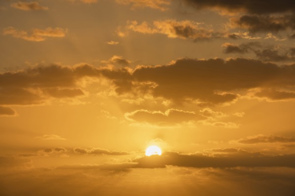 Golden sunrise sky with cumulus clouds and sun