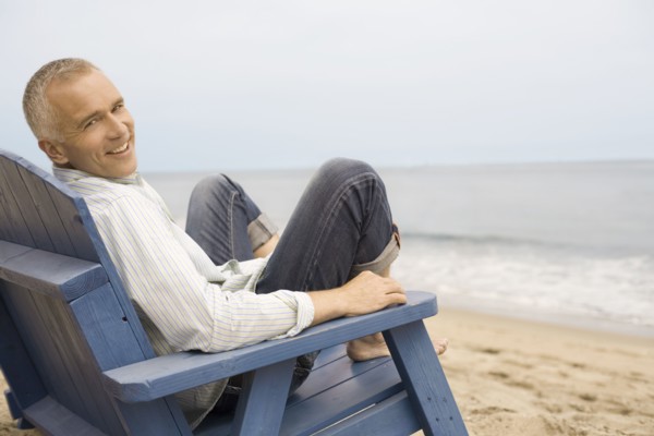 Portrait of mature man sitting in chair on beach