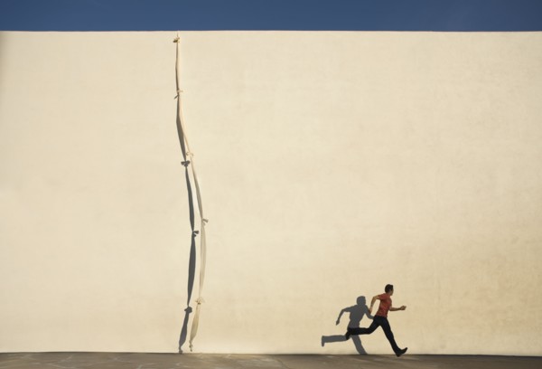 Man escaping by climbing rope over wall