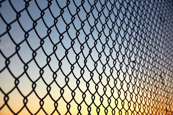 Chain link fence against sky at sunset