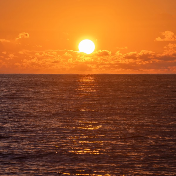 Sun rising above calm ocean