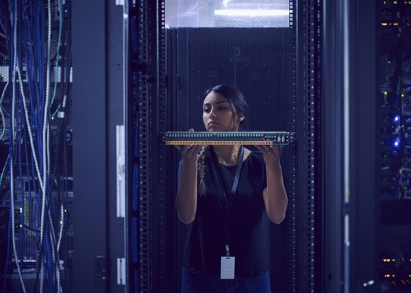 Female technician holding hard drive in server room