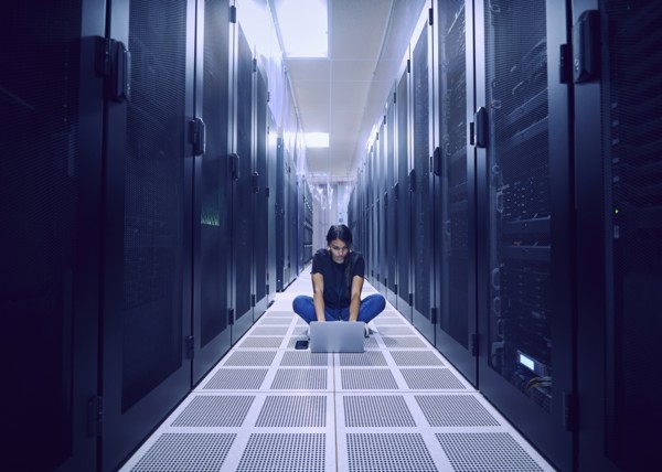 Female technician using laptop on floor in server room
