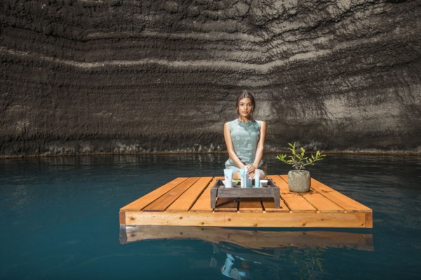 Beautiful woman kneeling on wooden raft on pond