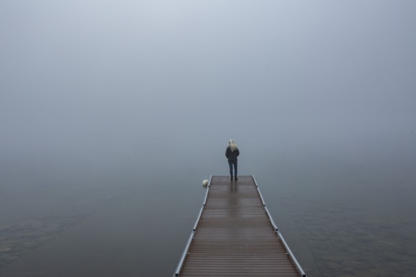 Back view of senior woman standing on jetty in morning