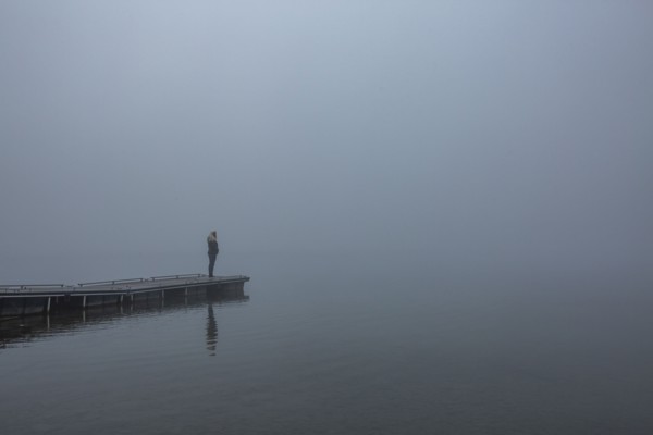 Woman standing on jetty in morning by lake