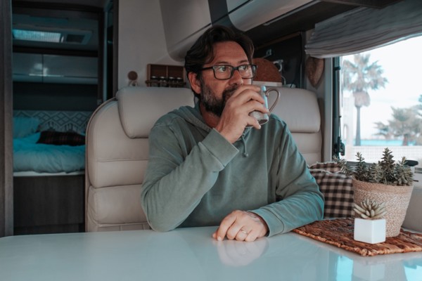 Man sitting in mobile home and drinking tea