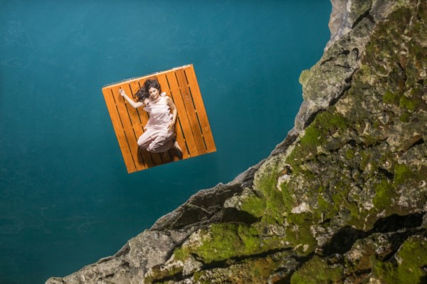 Overhead view of woman lying on floating dock near rocky coast
