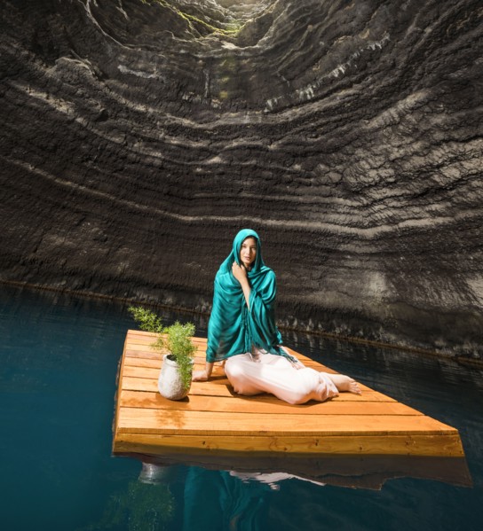 Portrait of woman sitting on floating dock near rocky coast