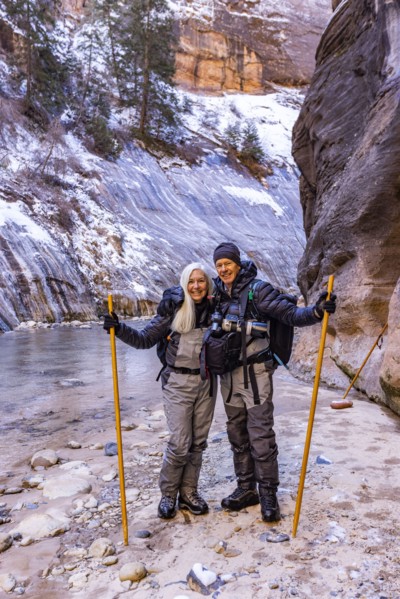Senior couple crossing river while hiking in mountains