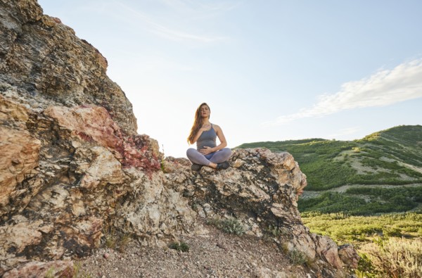 Mid adult woman meditating in mountains