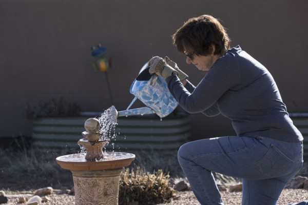 Woman filling bird bath with watering can