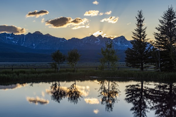 Scenic view of Sawtooth Mountains with pond at sunset
