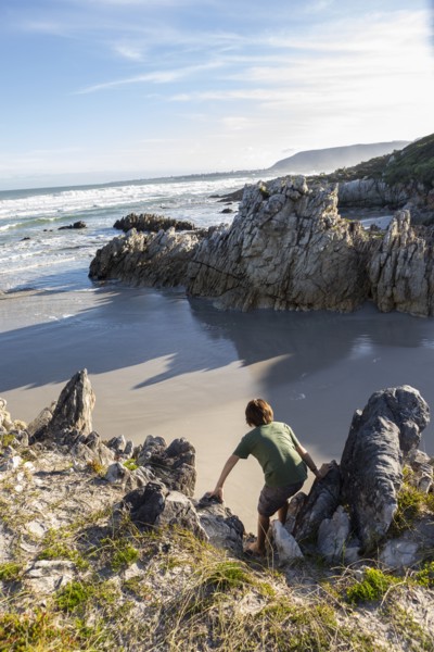 Boy exploring rocky coastline in Voelklip Beach