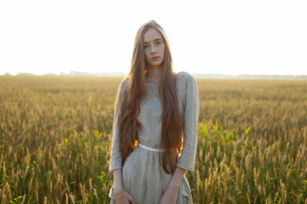 Portrait of young woman looking at camera while standing in field
