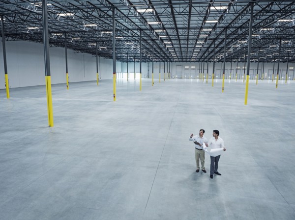 Architects with blueprint talking in empty warehouse