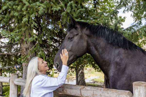 Senior woman stroking cheek of large Percheron draft horse