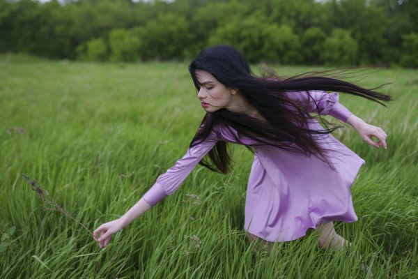 Portrait of young woman picking grass on meadow