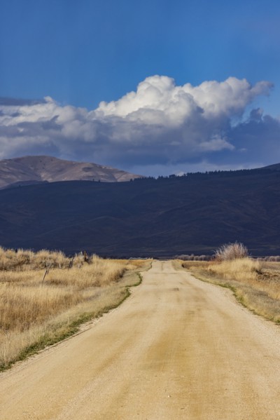 Empty dirt road leading to foothills under stormy skies, Fairfield, Idaho, USA