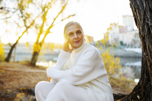 Portrait of woman in white sweater sitting by river in autumn, Omsk, , Russia