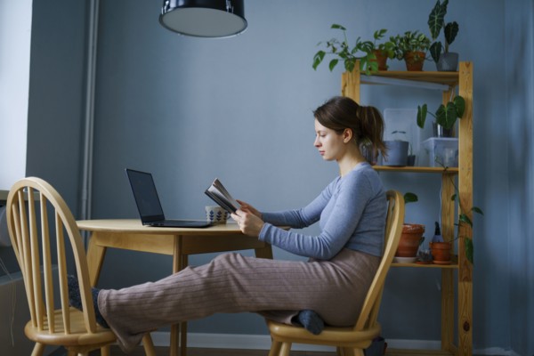 Woman reading at table at home, Omsk, , Russia