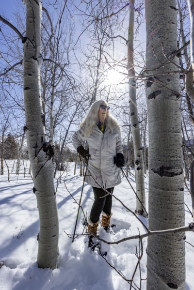 Smiling woman snowshoeing through aspen forest, Sun Valley, Idaho, USA