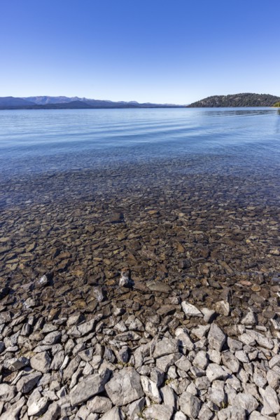 Rocky beach and calm lake on sunny day, Bariloche, , Argentina