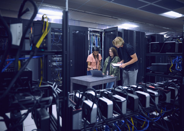 Group of technicians using laptop in server room 
St, George, Utah, USA