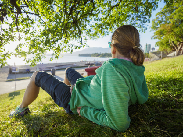 Rear view of woman sitting on lawn near coast
Vancouver, British Columbia, Canada