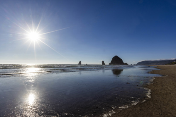 USA, Oregon, Sun setting over ocean and empty Cannon Beach