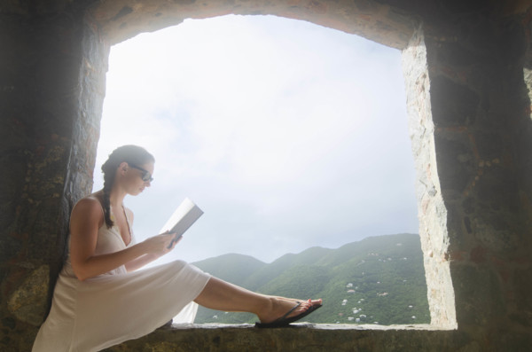 USA, United States Virgin Islands, St. John, Young woman reading in window of villa