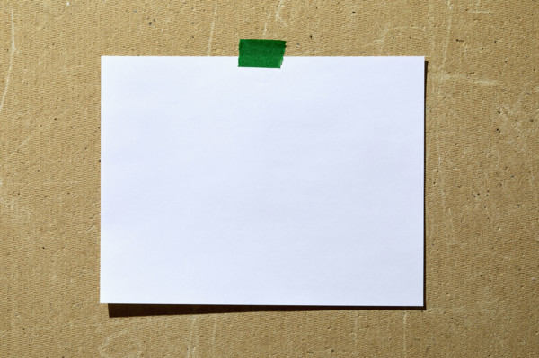 Blank paper taped to rough textured wall