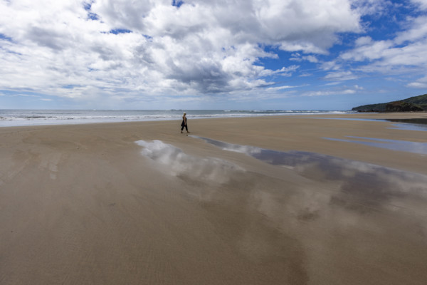 Costa Rica, Guanacaste, Playa Grande, Woman walking on empty beach at low tide