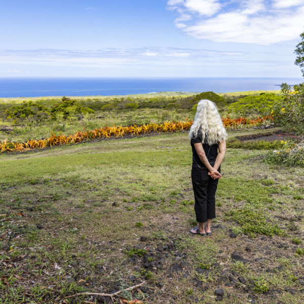 Rear view of woman standing in garden, facing ocean. Kona, Hawaii, USA.
