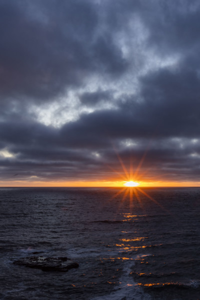 Dark clouds and sun stetting above ocean. La Jolla, California, USA.