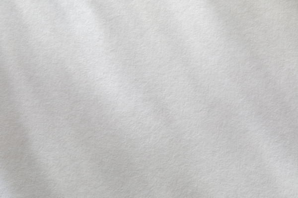 Dappled light on textured white paper. New York City, New York State, USA.