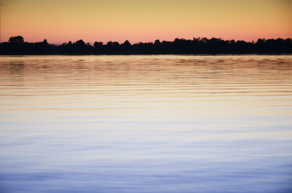 Calm Black Lake reflecting sky at sunset. Hammond, New York State, USA.