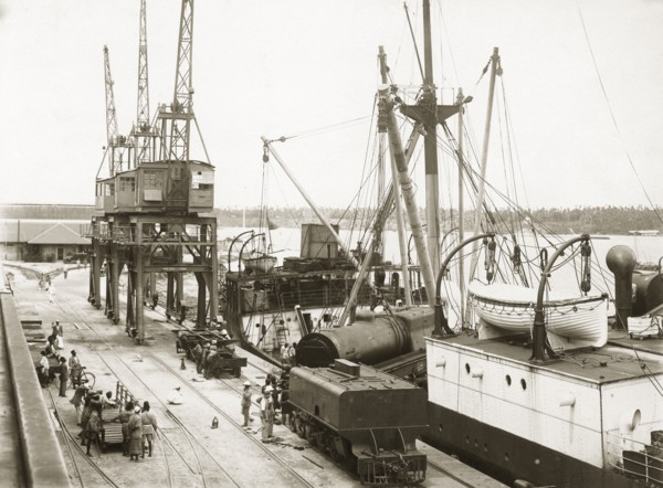 Unloading a train from SS Harmonides. Cranes onboard SS Harmonides hoist a locomotive boiler onto