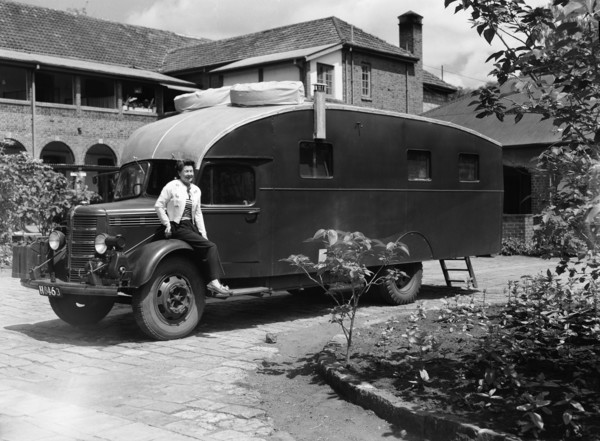 The Price's caravan. A woman sits on the wheel-arch of an old-fashioned caravan in the driveway to