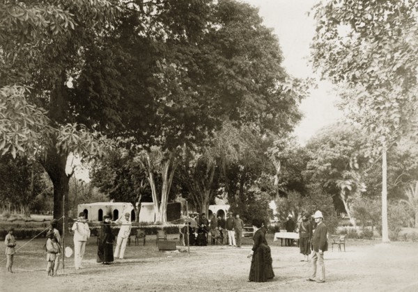Mixed-sex tennis match. A small gathering of onlookers watches a tennis match between a group of