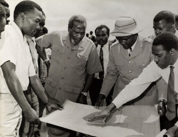 Jomo Kenyatta meets town planners. Farm planners gather around a blueprint to explain their