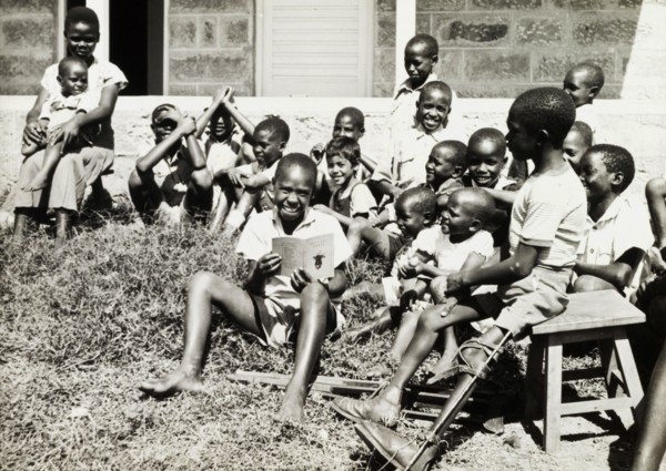 Children at a charity in Nairobi. An older boy reads a story to a group of younger children on a