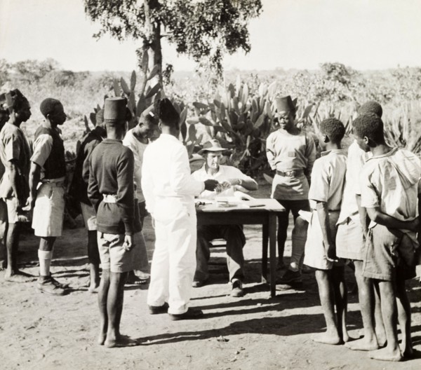 African workers collecting their pay. Young African men in Western-style clothing form a queue at a