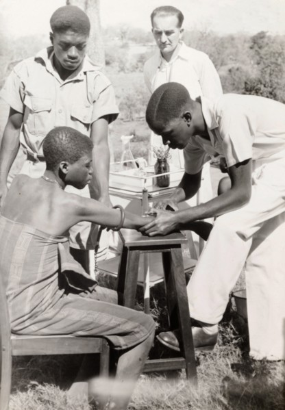 An African medic injects a patient. An African medic gives an injection to a female patient, while