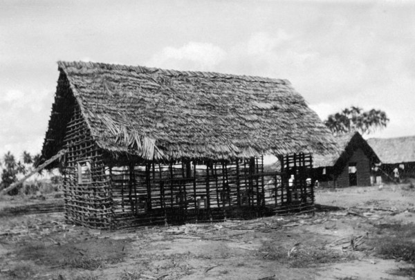 Framework for a new classroom. The timber framework and thatched roof of a classroom being built by