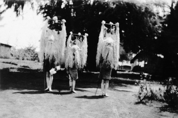 Nandi youths wearing circumcision masks. Three Nandi youths wear tall, elaborate grass headdresses