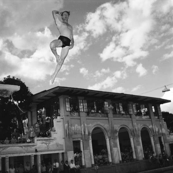 Crazy diving. A man wearing trunks at a swimming gala launches himself into the air from a diving