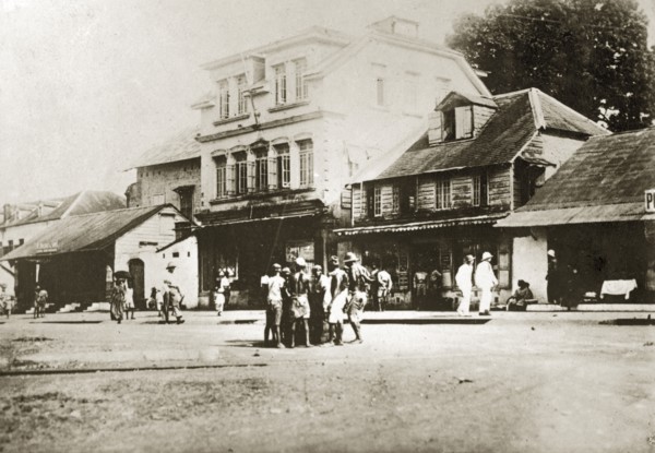 A main street in Sierra Leone. Africans and Europeans mill about on a wide main road in the centre