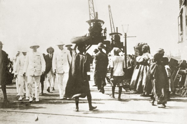 Landing stage. An African man carrying a basket of bananas on his head, weaves through a crowd at a
